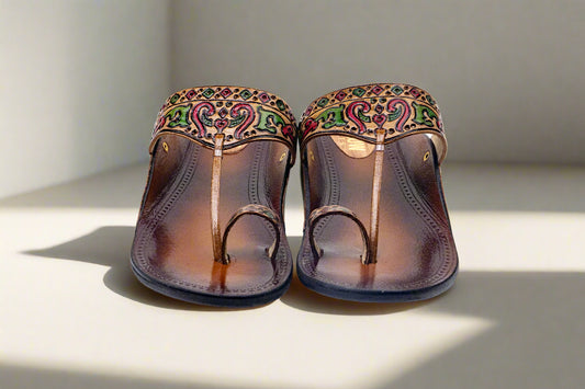 Pair of brown sandals with decorative straps on a white background