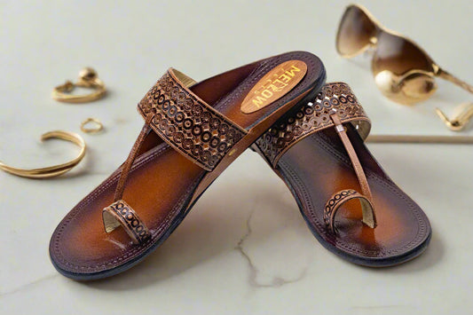 Pair of brown sandals with embellishments on a white background