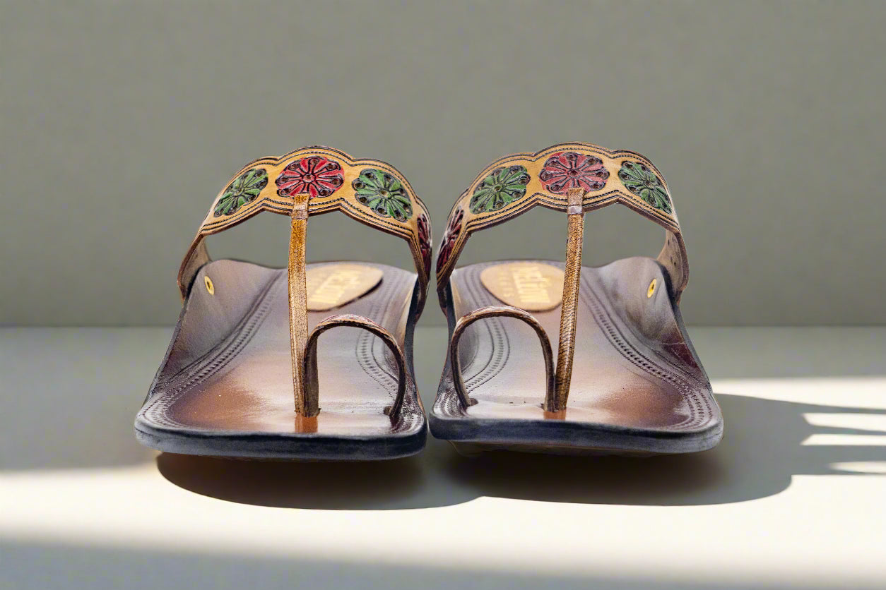 Pair of decorative sandals with floral patterns on a neutral background