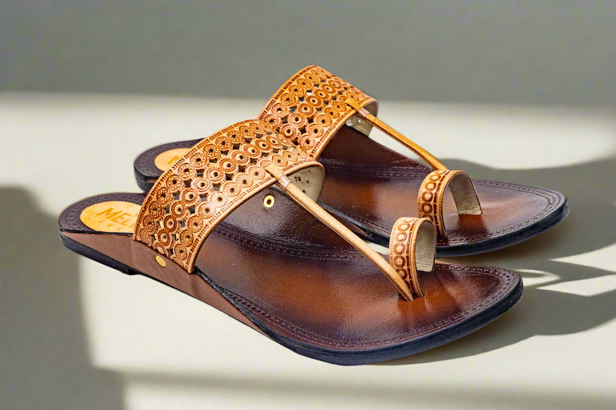Artisanal brown leather flats with intricate floral embossing, featuring a toe-loop design and soft cushioned insole — crafted by Mellow Feets for timeless elegance and everyday grace.