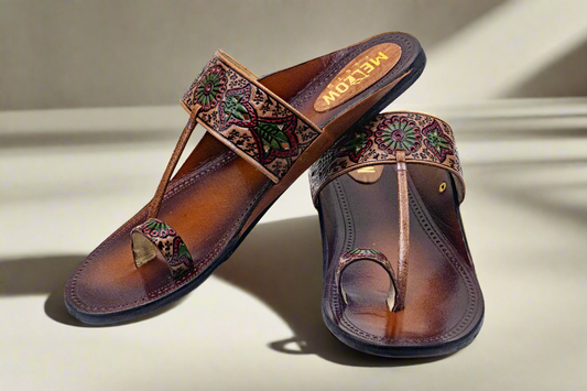 Pair of brown sandals with decorative straps on a light background