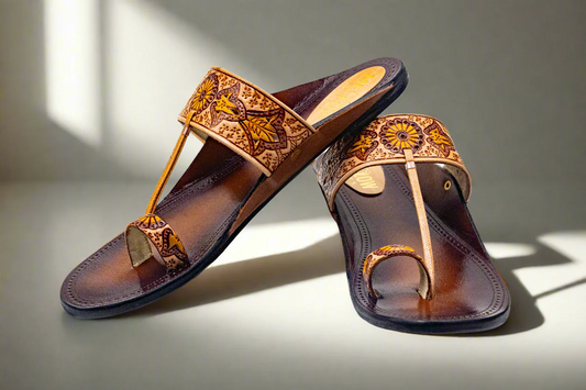 Pair of brown sandals with decorative straps on a light surface.