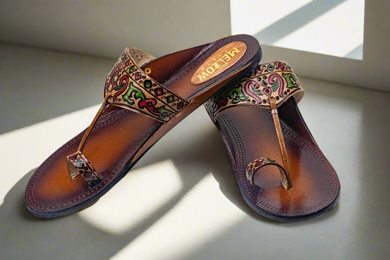 Pair of brown sandals with decorative patterns on a light surface