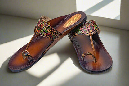 Pair of brown sandals with decorative patterns on a light surface