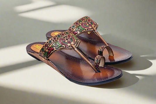 Pair of brown sandals with colorful embellishments on a light background