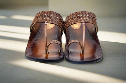 Pair of brown sandals with decorative straps on a white background