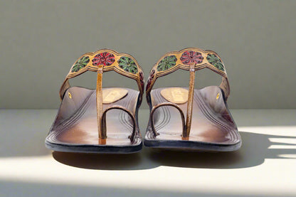 Pair of decorative sandals with floral patterns on a neutral background