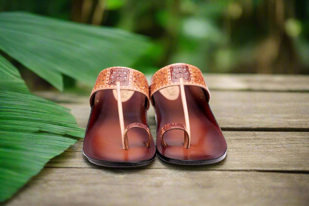 Pair of brown sandals with decorative straps on a white background