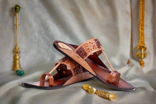 Pair of brown sandals with decorative straps on a white background