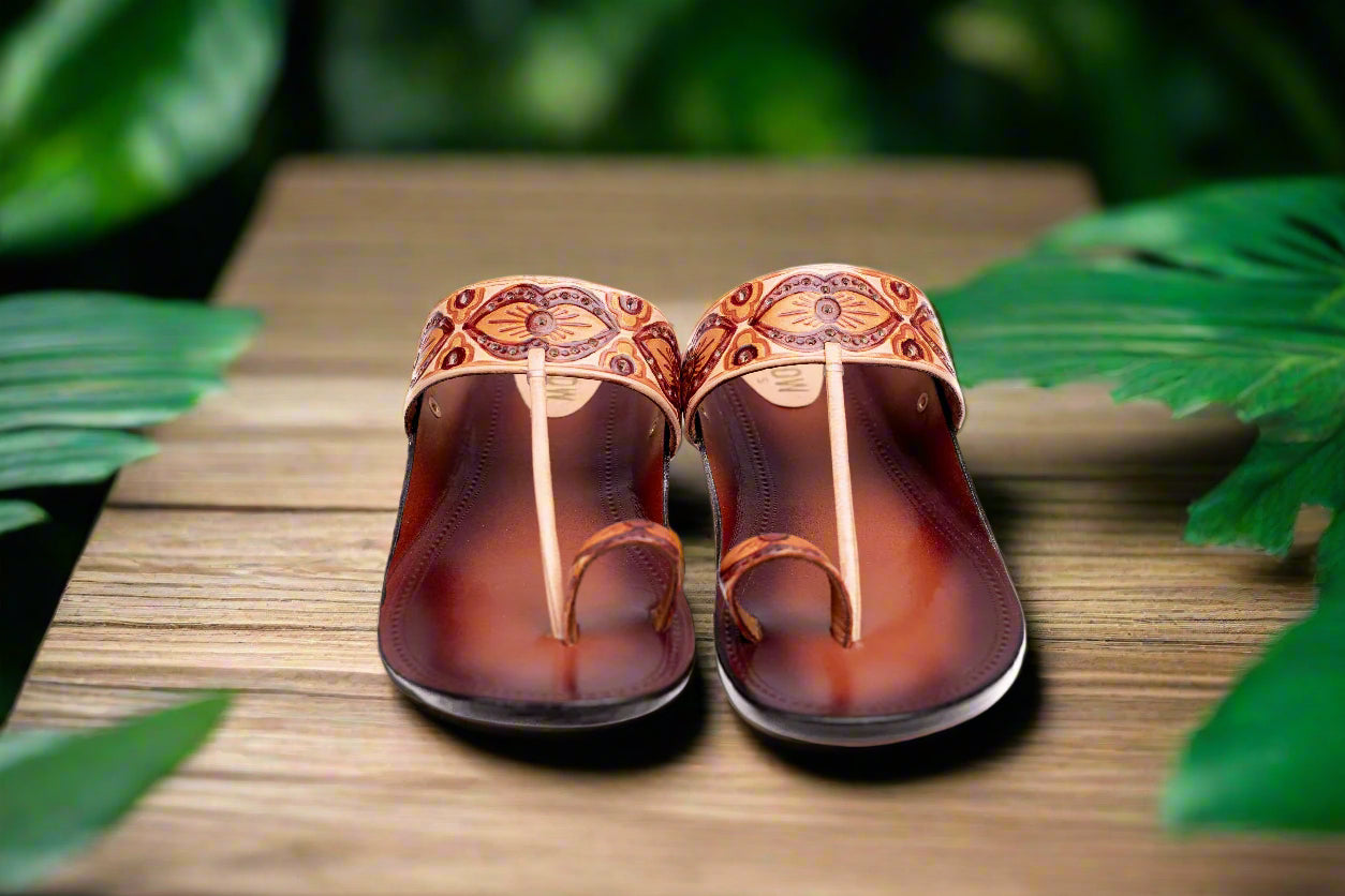 Pair of brown sandals with decorative straps on a wooden surface