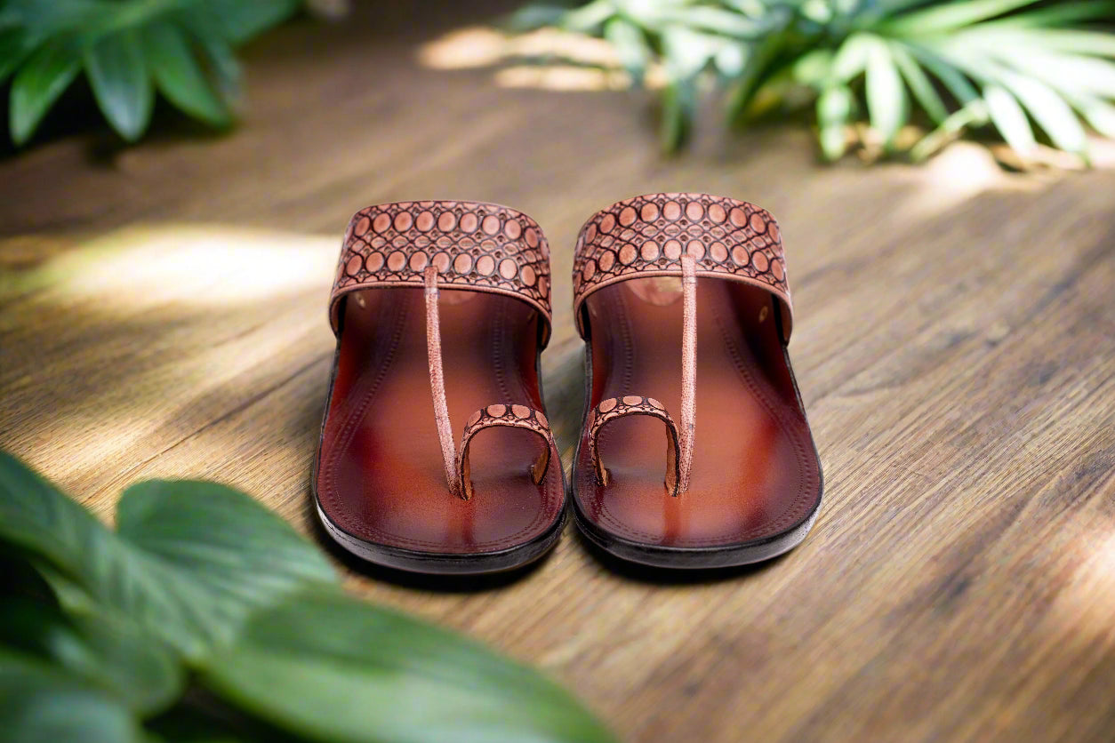 Pair of brown sandals with decorative straps on a white background