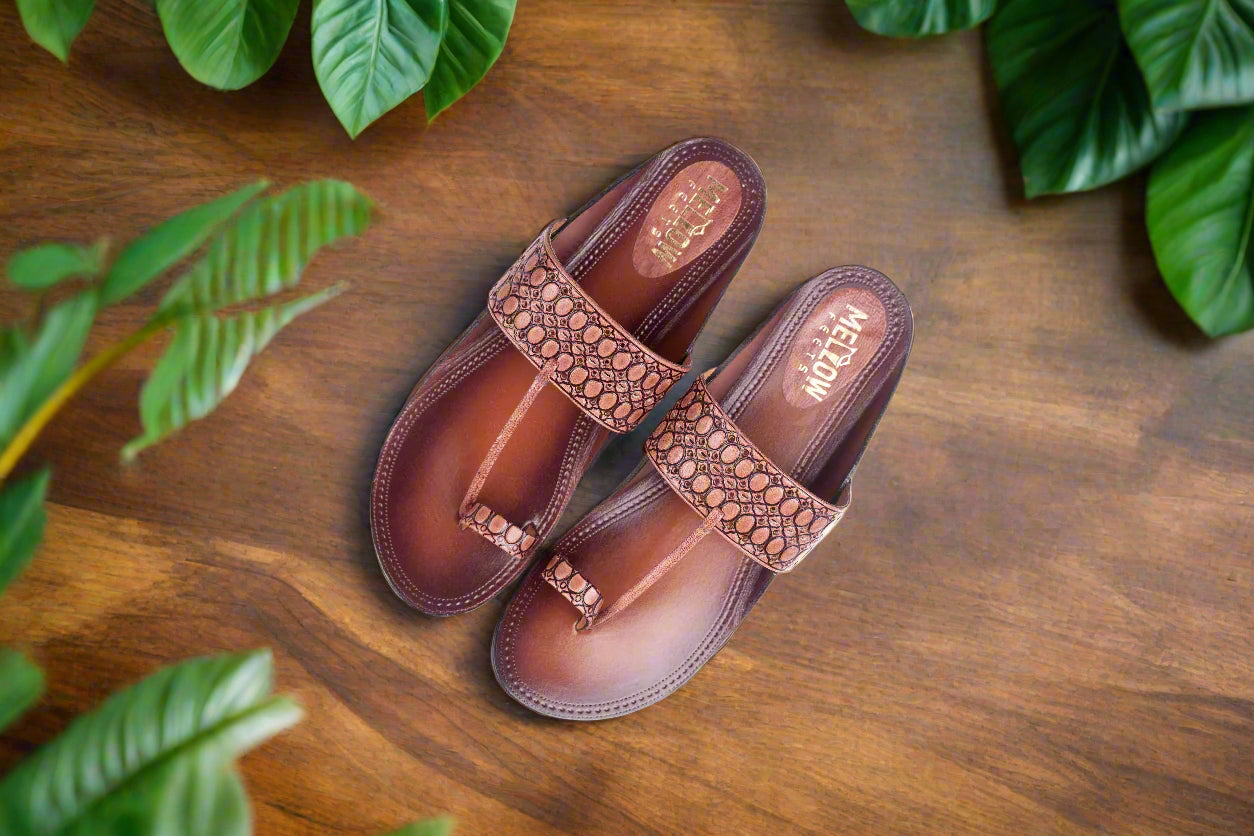 Pair of maroon sandals with decorative straps on a light background