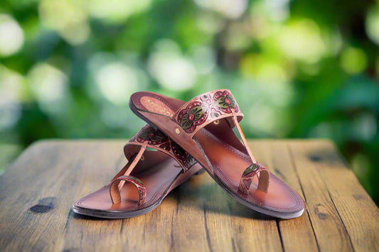 Pair of brown sandals with floral designs on a white background