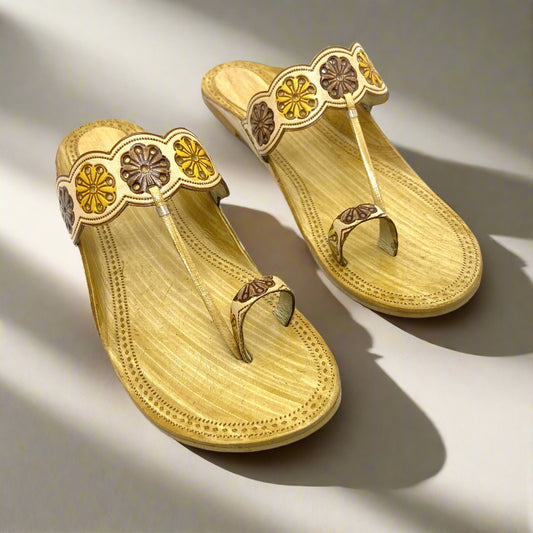 Beige handcrafted Kolhapuri flats with yellow and brown floral embossed strap design, carved sole texture, and ethnic toe loop detailing for women