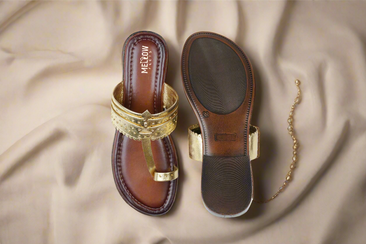 Brown sandal with gold accents on a beige fabric background