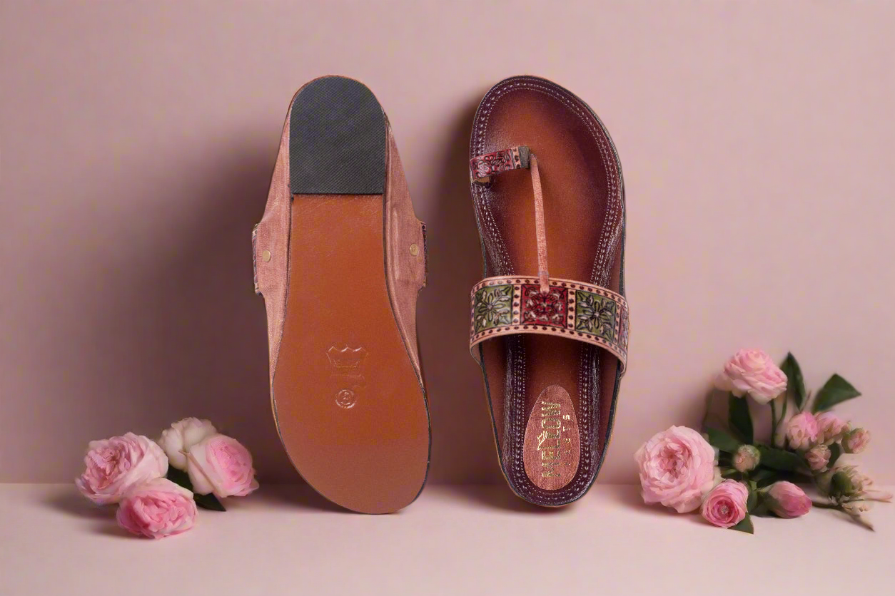 Pair of sandals with floral embellishments on a light pink background with flowers.