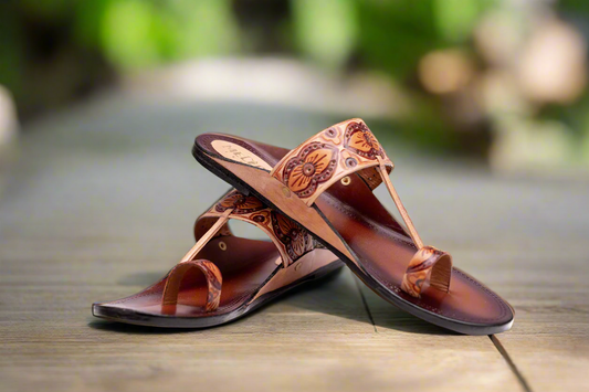 Pair of brown sandals with intricate designs on a wooden surface