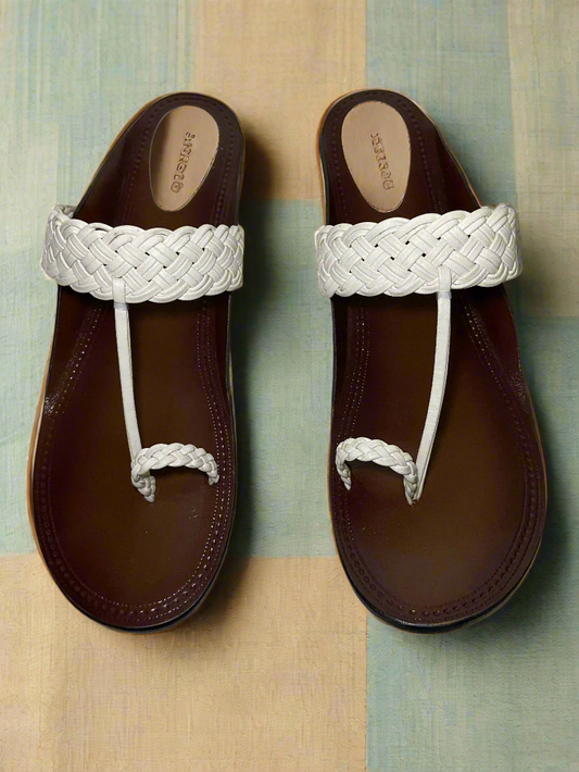Pair of brown sandals with white braided straps on a neutral background