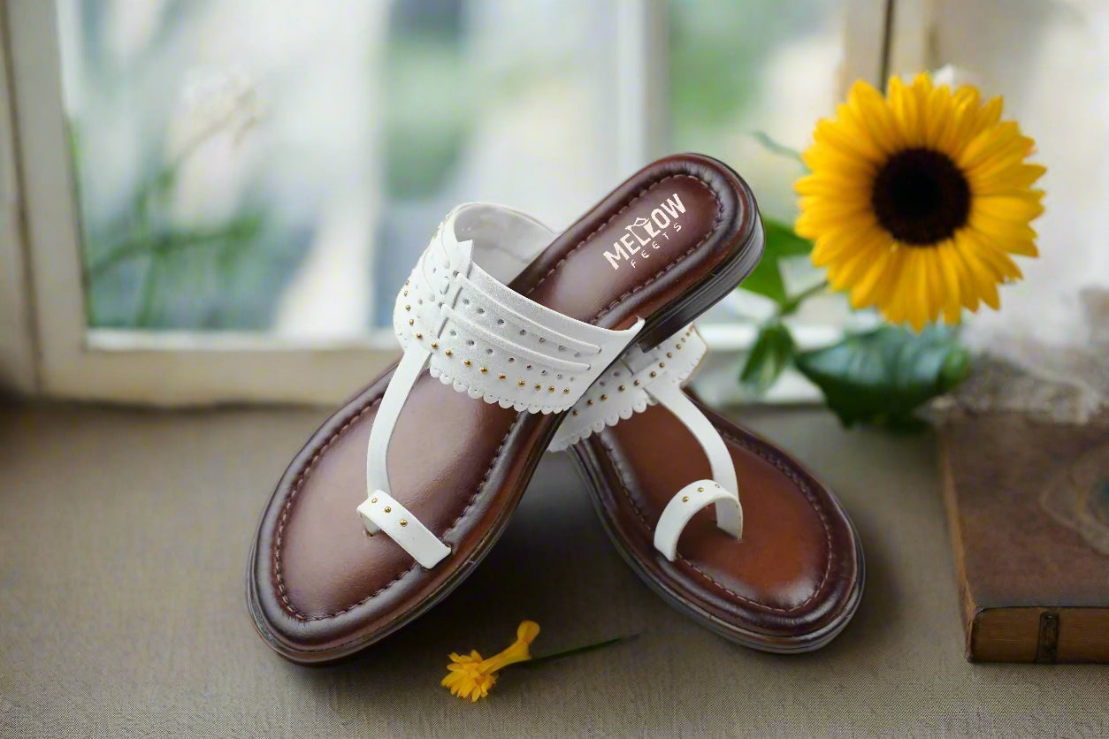 Traditional Indian Kolhapuri sandals in white with golden studs, displayed pair on white surface